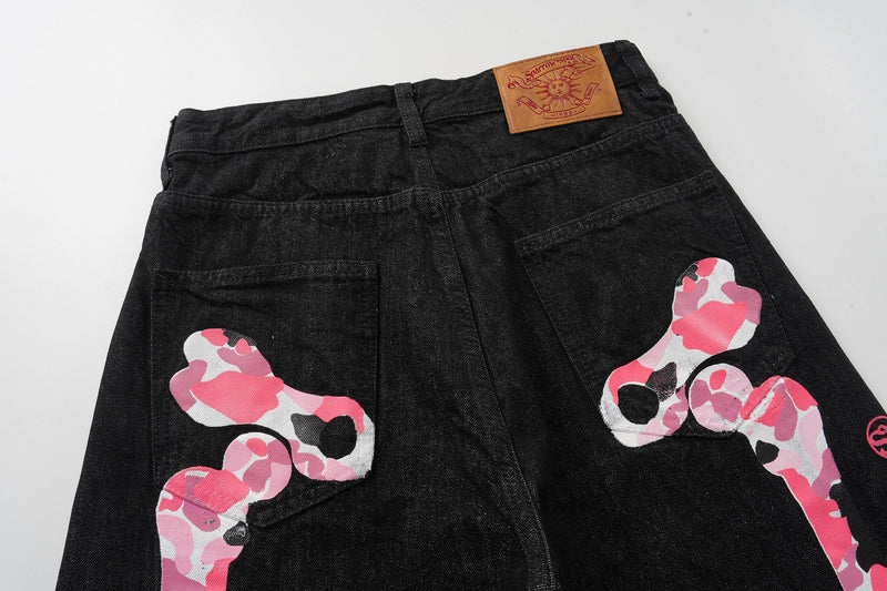 Back view of black wide-leg denim pants with pink camouflage skeleton graphics and leather patch
