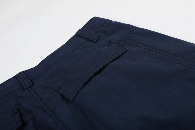 Close-up of navy cargo pants side pocket flap and waistband stitching