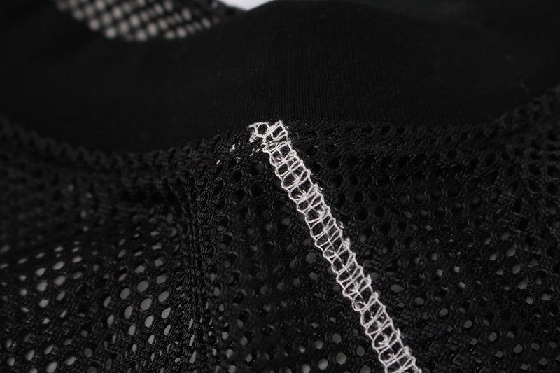 Close-up of black mesh jersey fabric with white contrast stitching and textured athletic streetwear detail