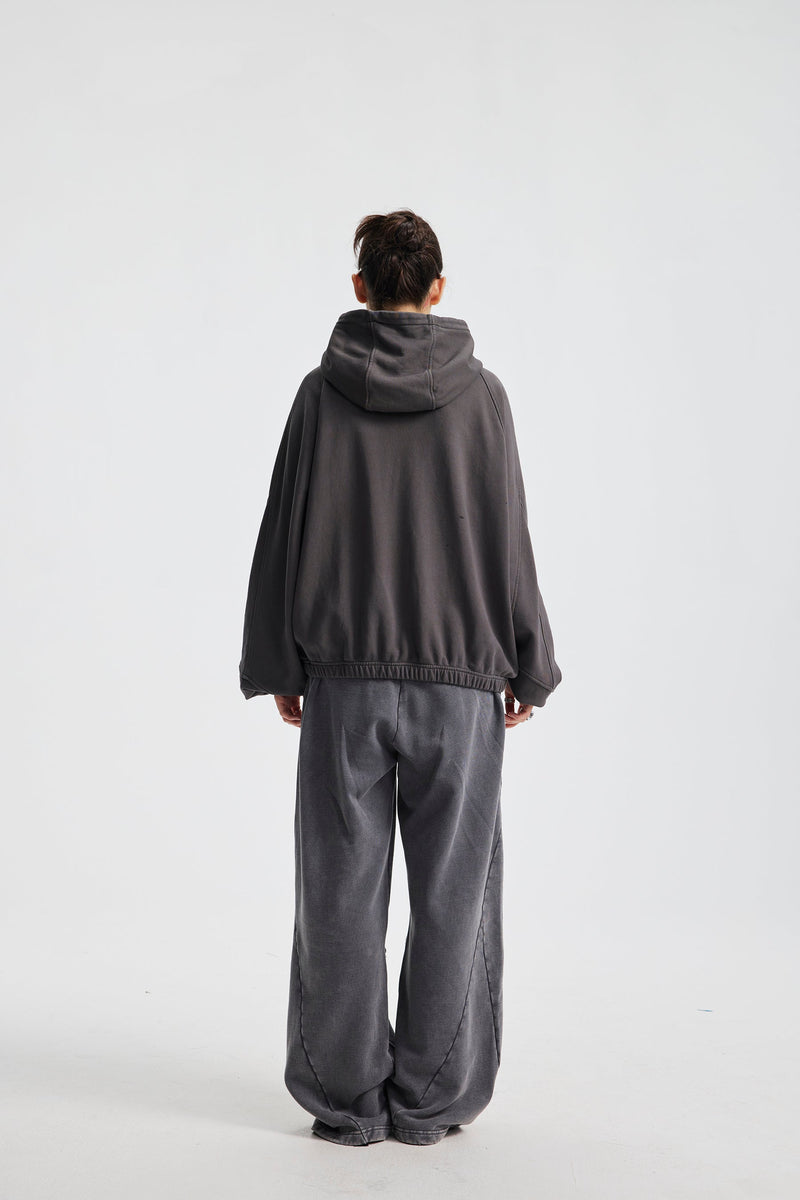 Back view of a model wearing charcoal gray hoodie with hood down and wide-leg pants