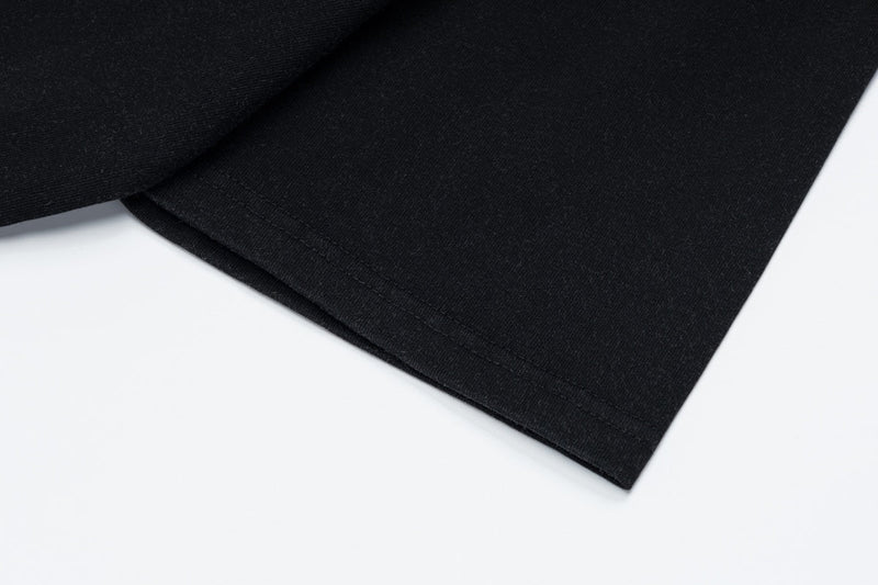 Black vintage graphic tee sleeve hem on white background, close-up of soft cotton fabric and stitching