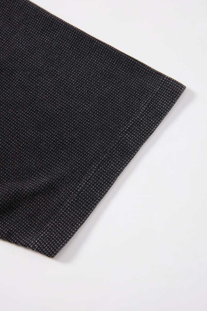 Close-up of black textured fabric with a fine woven pattern on a white background