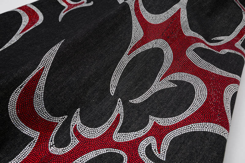 Close-up of black denim with large red and silver rhinestone flame motif