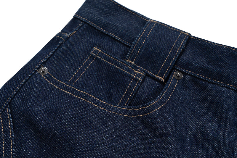 Close-up of the front waistband and coin pocket on raw indigo denim jeans