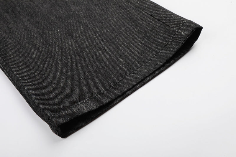 Close-up of black denim hem with wide leg opening and stitched cuff
