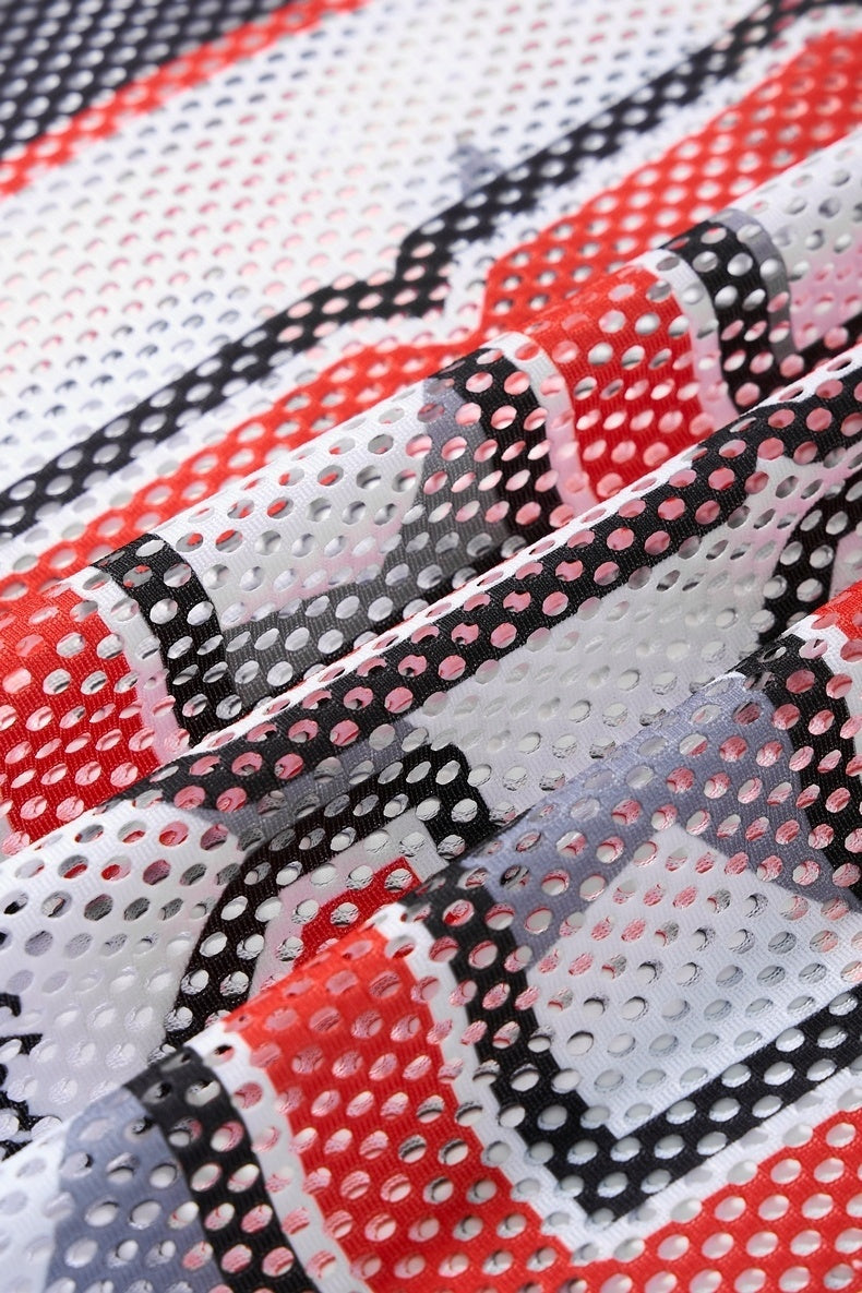 Close-up of red, black, and white mesh football jersey fabric with perforated streetwear pattern and textured folds