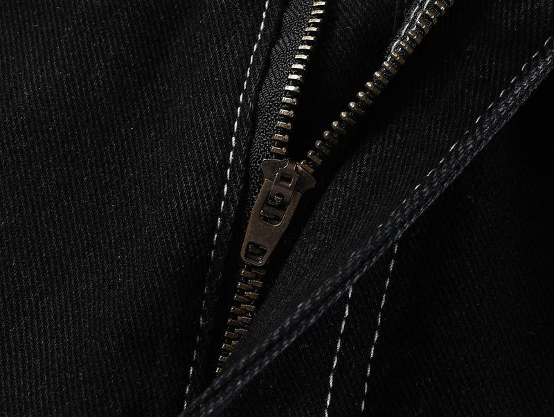 Close-up of the black denim zipper fly and white stitched seam detail