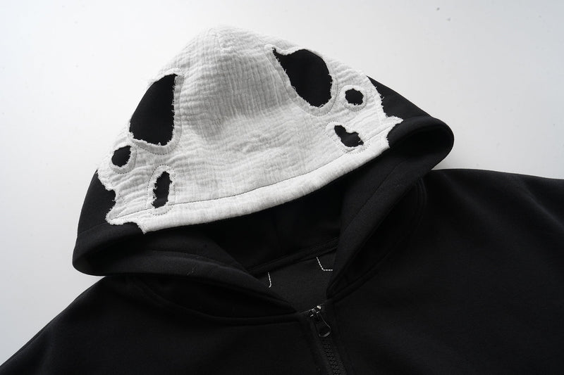 Close-up of white hood lining with cutout holes on black zip-up hoodie