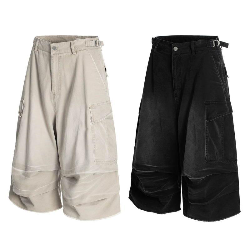 Washed cargo shorts shown in beige and black with wide legs, buckle belt loops, and layered panel fronts
