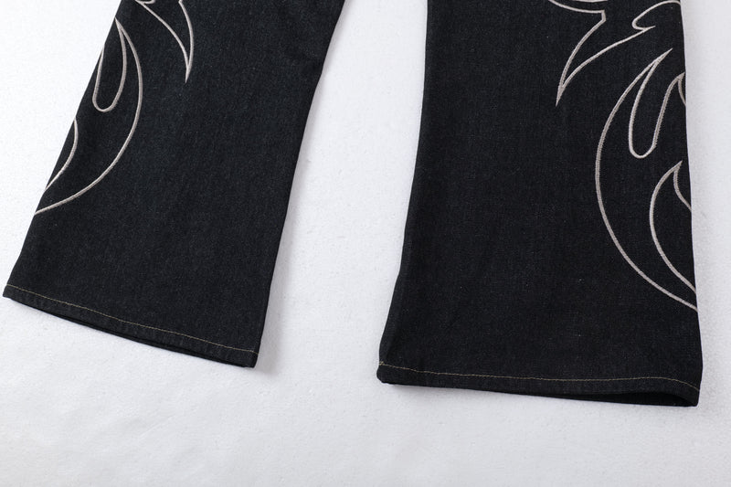 Lower hem close-up of dark wide-leg jeans with tribal embroidery and stitched cuffs