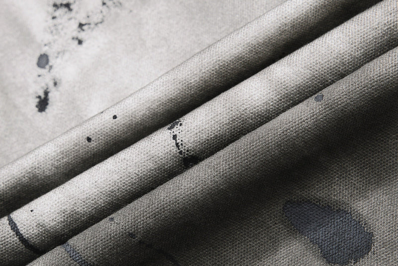 Close-up of folded gray denim fabric with visible weave and splatter marks