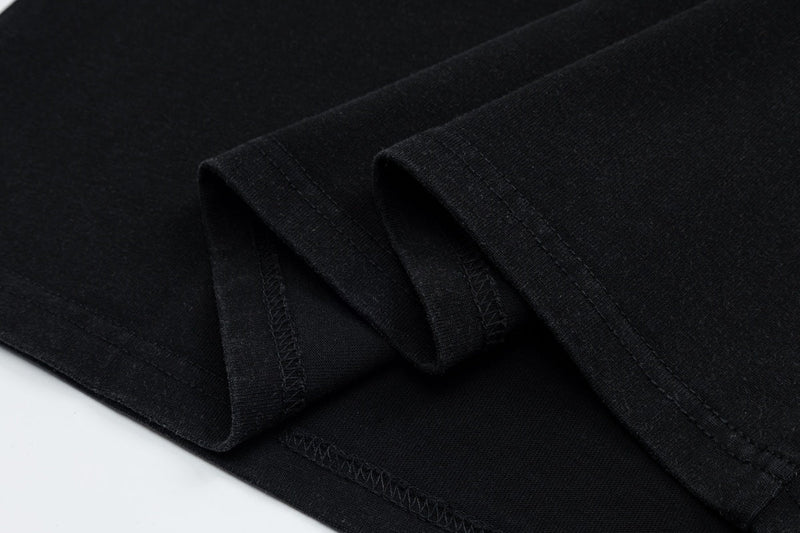 Black vintage graphic tee sleeve detail with folded hem and visible stitching on soft cotton fabric