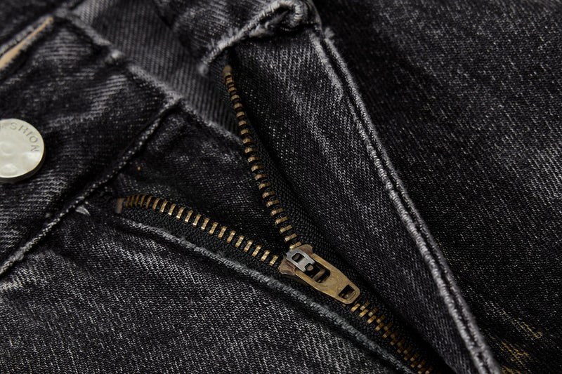 Close-up of metal zipper and button on black denim pants