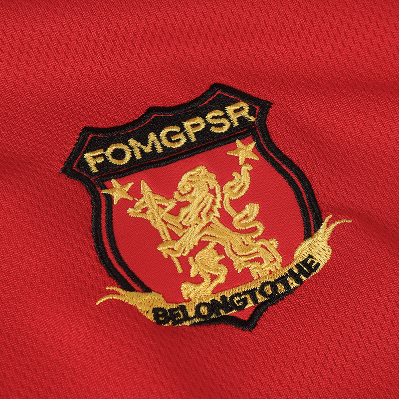 Red football jersey fabric with embroidered gold crest and black shield emblem on the chest