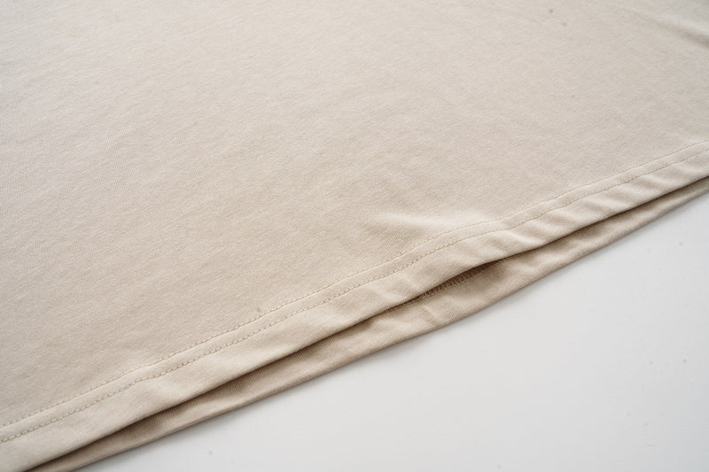 Close-up of a beige camo raglan T-shirt hem with visible stitching and soft cotton fabric texture