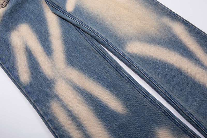 Leg detail of blue wide-leg jeans with cream spray-fade graffiti wash