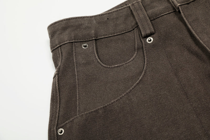 Close-up of brown pants front pocket and waistband stitching