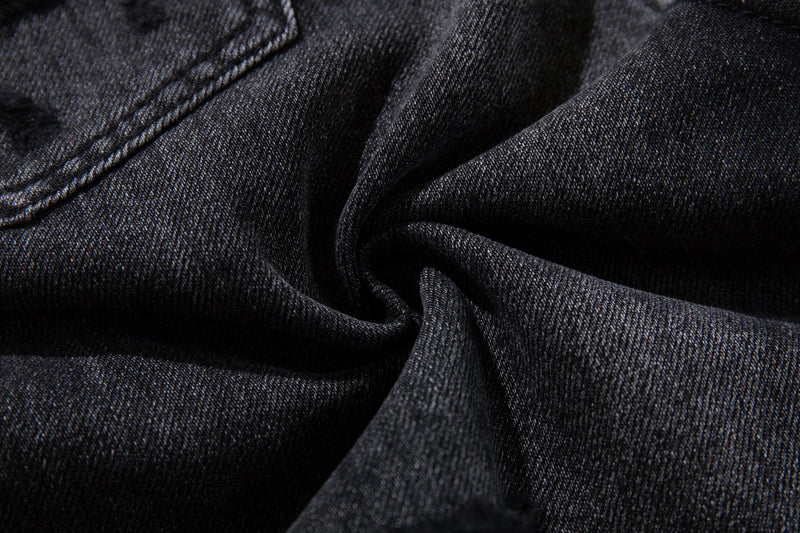 Close-up of dark charcoal denim fabric with visible weave and stitched seam