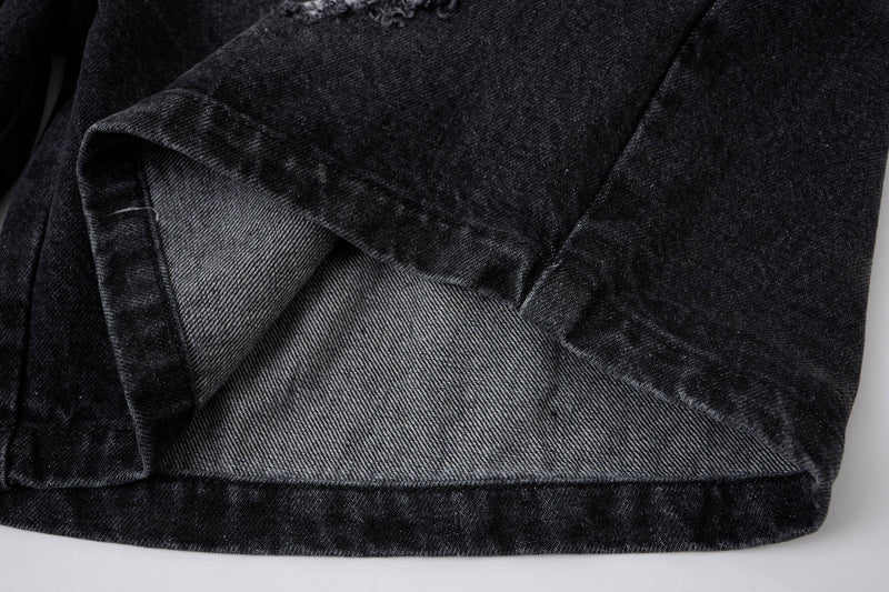 Close-up of black denim shorts hem showing inner seam and folded edge