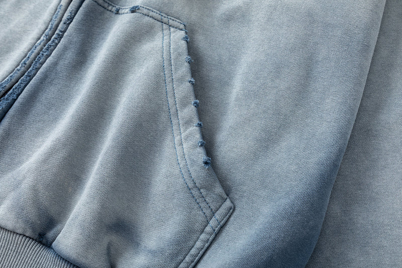 Close-up of front kangaroo pocket on washed blue hoodie with stitched edge details
