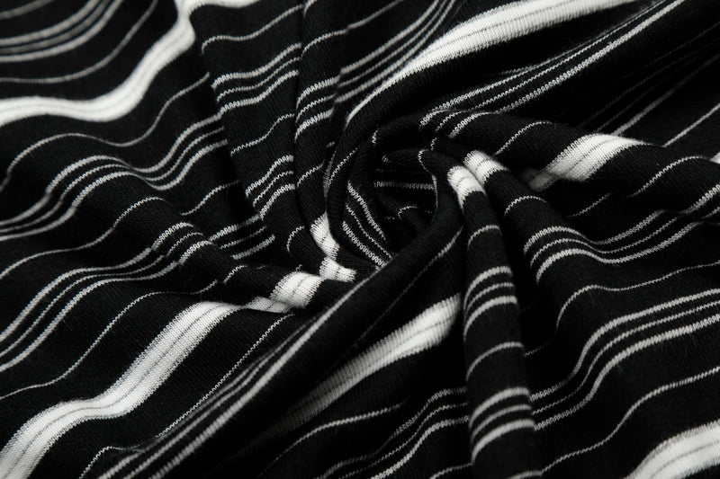 Close-up of gathered black striped fabric with thin white lines and distressed texture