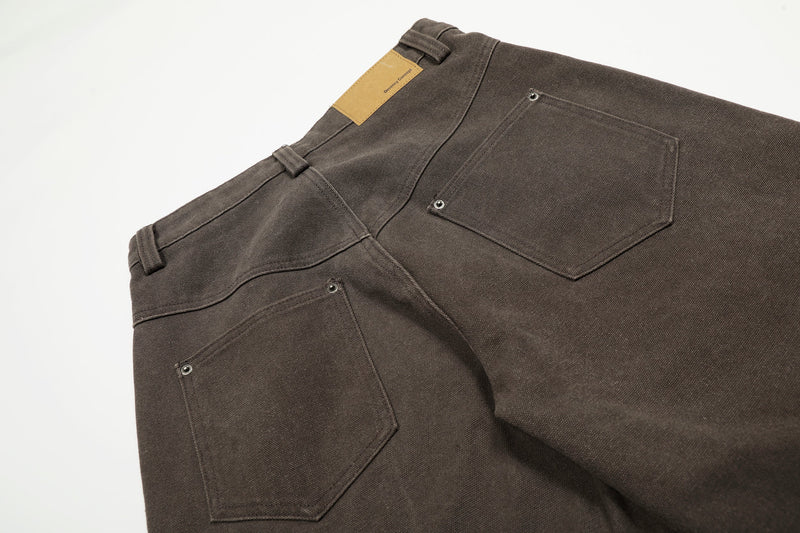 Back pocket detail on brown wide-leg workwear pants with a tan label at the waistband