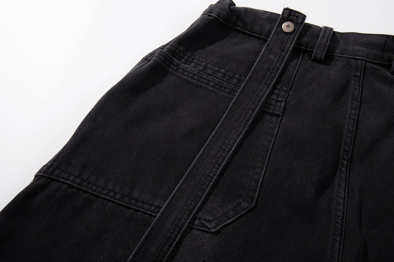 Close-up of front waist and strap detail on dark washed denim jeans