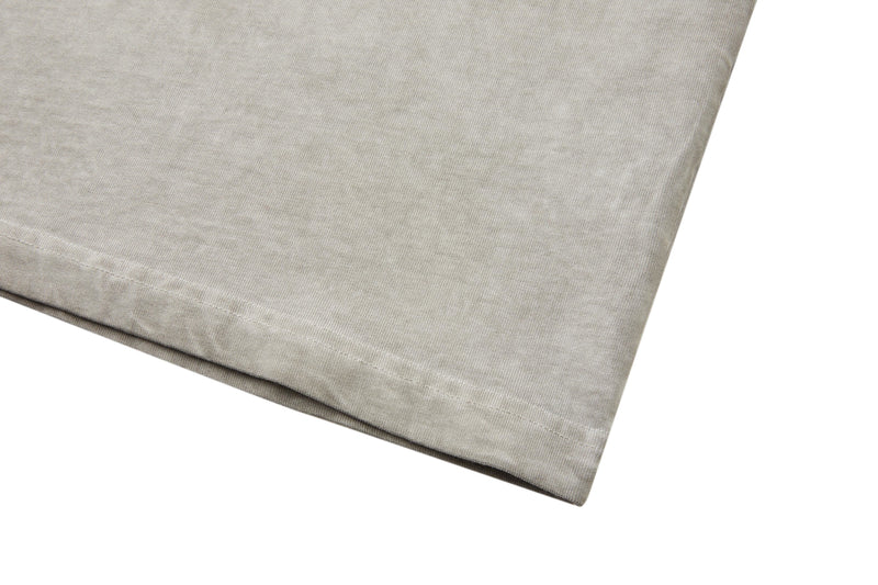 Close-up of a vintage washed beige heavyweight cotton tee hem with subtle stitched detailing