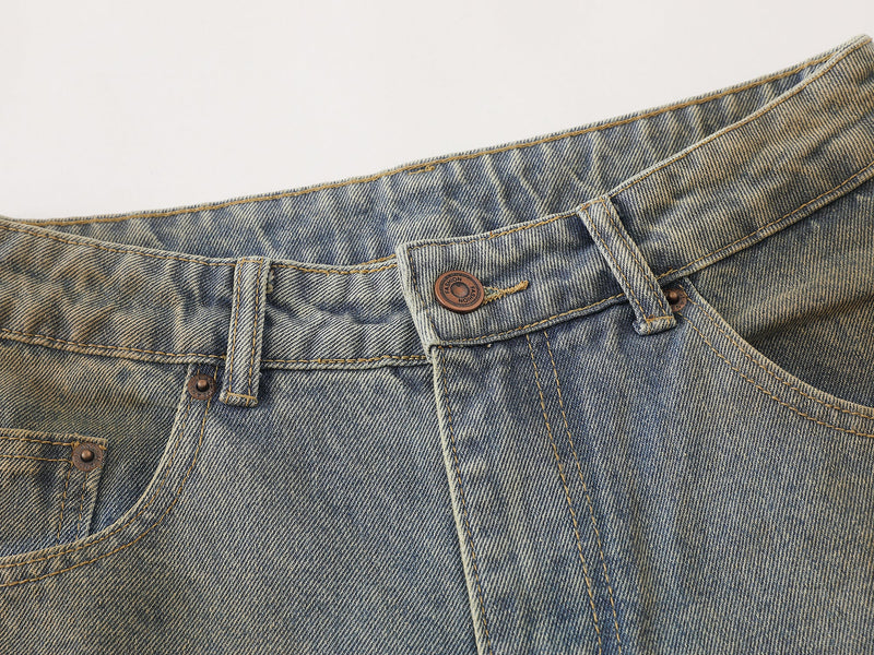 Close-up of the waistband on faded blue denim pants with button closure, belt loops, and contrast stitching