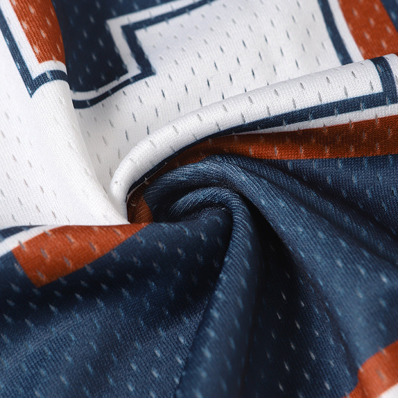 Close-up of a white, navy and orange mesh football jersey with star and stripe details, folded fabric texture visible