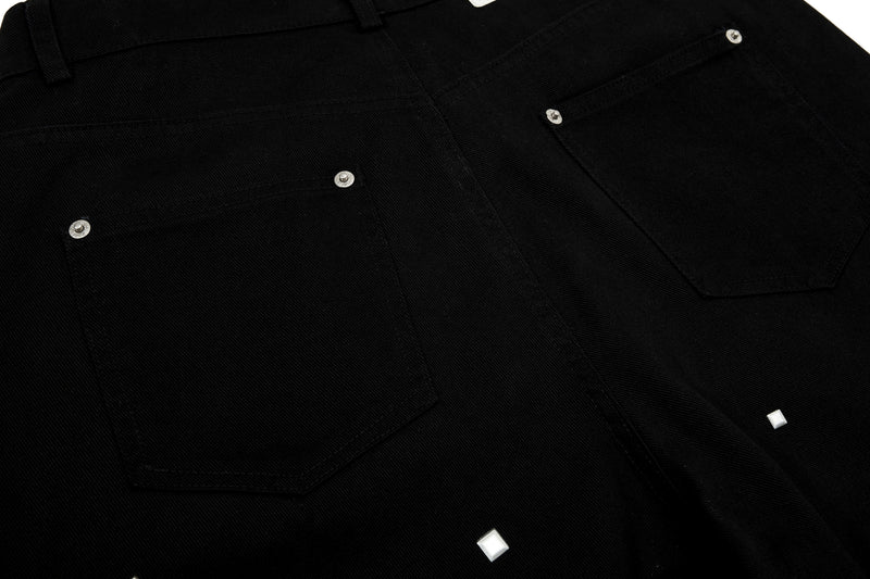 Close-up of black denim back pocket with silver studs