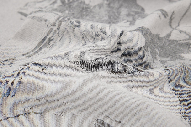 Close-up of textured gray denim fabric with abstract black brushstroke print