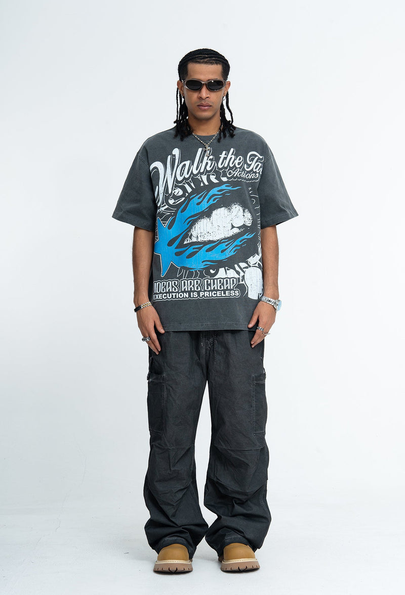 Vintage washed charcoal graphic T-shirt with blue and white slogan print, worn with wide black pants and tan boots