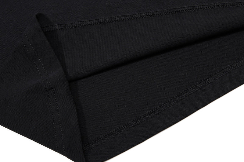 Close-up of black polo shirt fabric with stitched hem and sleeve seam, showcasing a vintage streetwear style for men