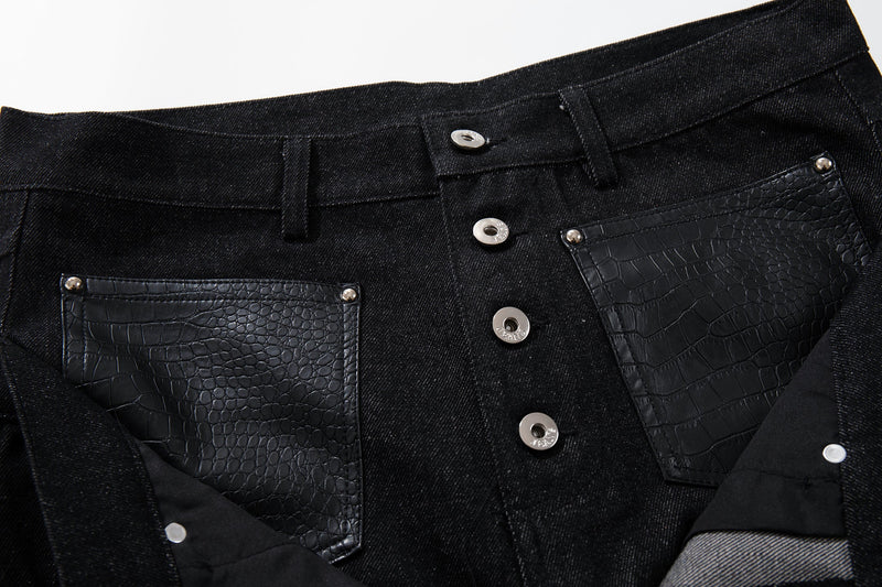 Close-up of front waist on black button-fly denim pants with faux crocodile pockets