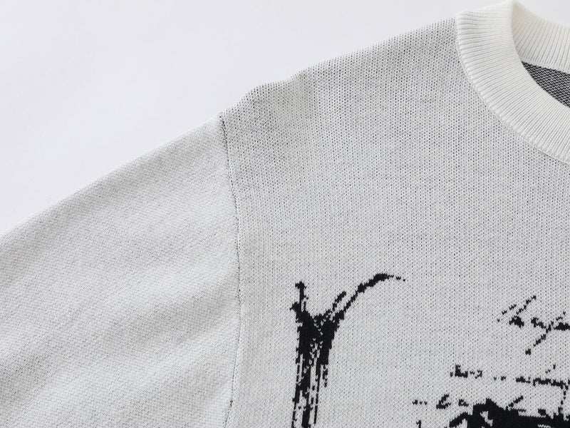 Close-up of white knit sweater shoulder and neckline with black cross graphic edge