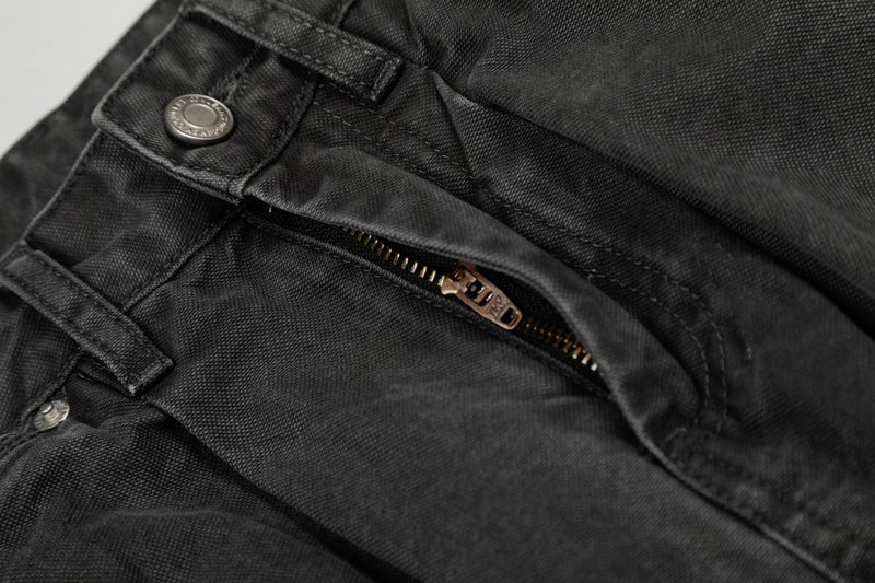 Close-up of the front fly zipper and button on washed black cargo denim pants