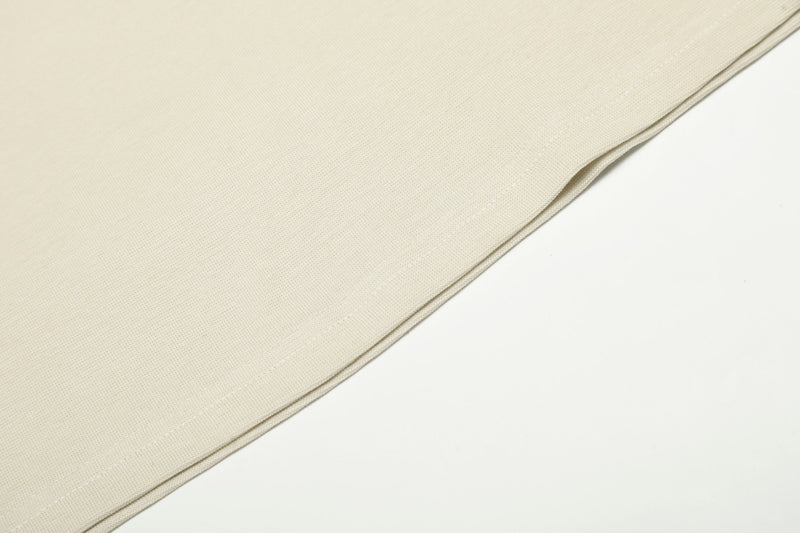 Cream fabric close-up showing fine knit texture and hem seam