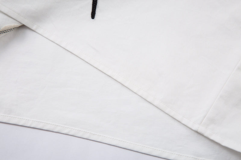 Close-up of white shirt hem and side seam over black underlayer