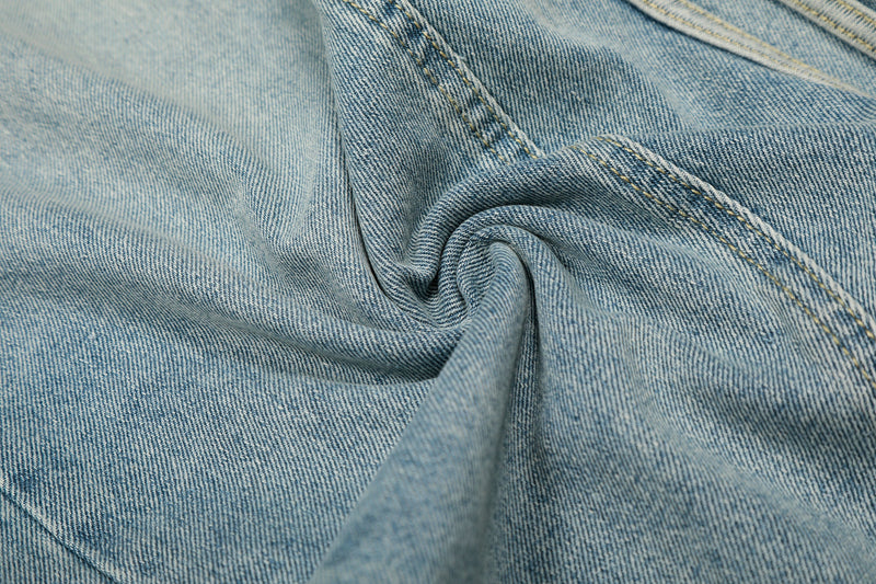 Close-up of light wash denim fabric and seam stitching with gathered fold