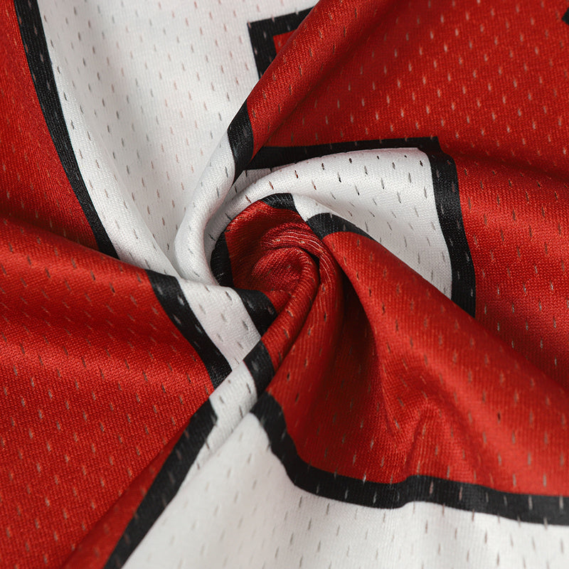 Close-up of red and white mesh football jersey fabric with bold black trim and printed graphic detailing