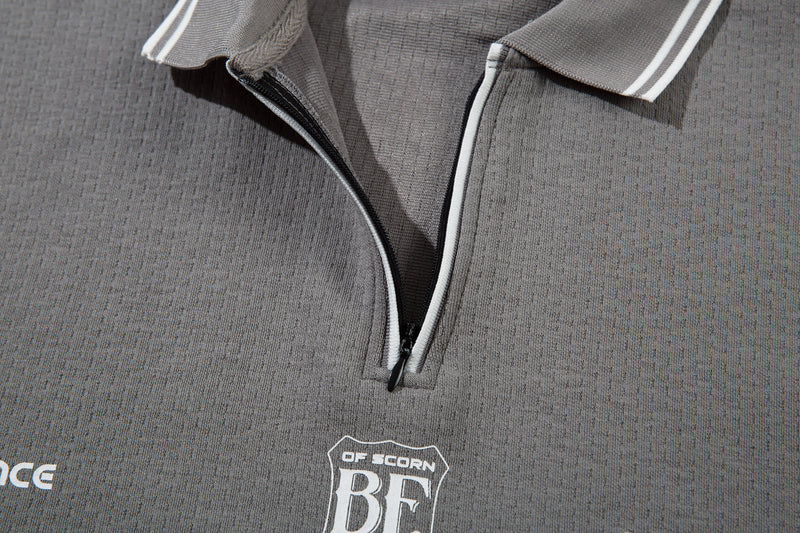 Close-up of gray polo zip placket and chest logo with printed 02 detail