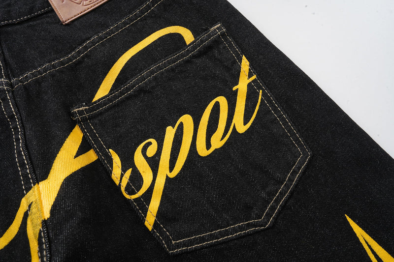 Back pocket close-up on black jeans with yellow script lettering