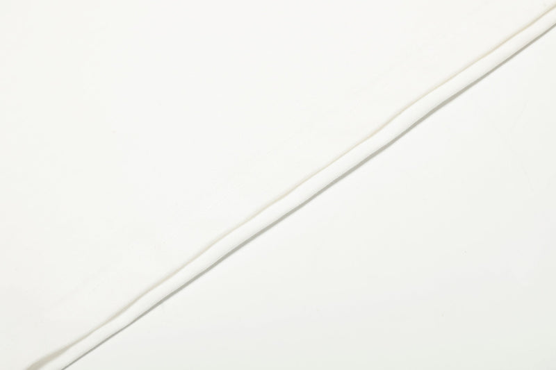 Close-up of white fabric panel on the tee with soft fold and seam detail