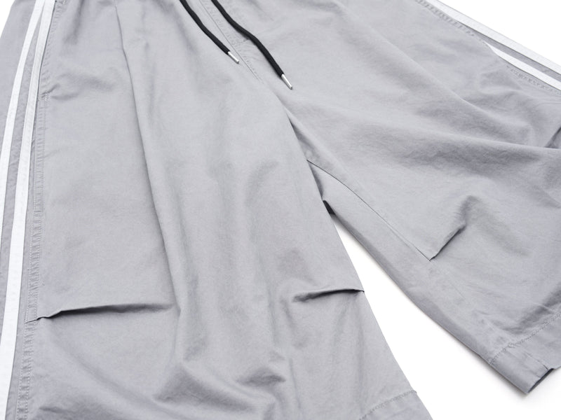 Front view of gray shorts with wide legs, side stripes, and black drawstring waistband