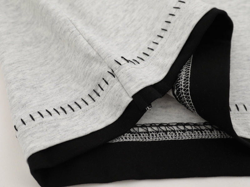 Close-up of cuff hem showing layered gray and black knit seams with visible stitching