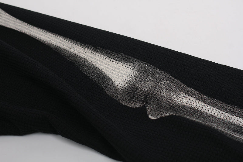 Close-up of sleeve hem on black waffle-knit tee with white bone print