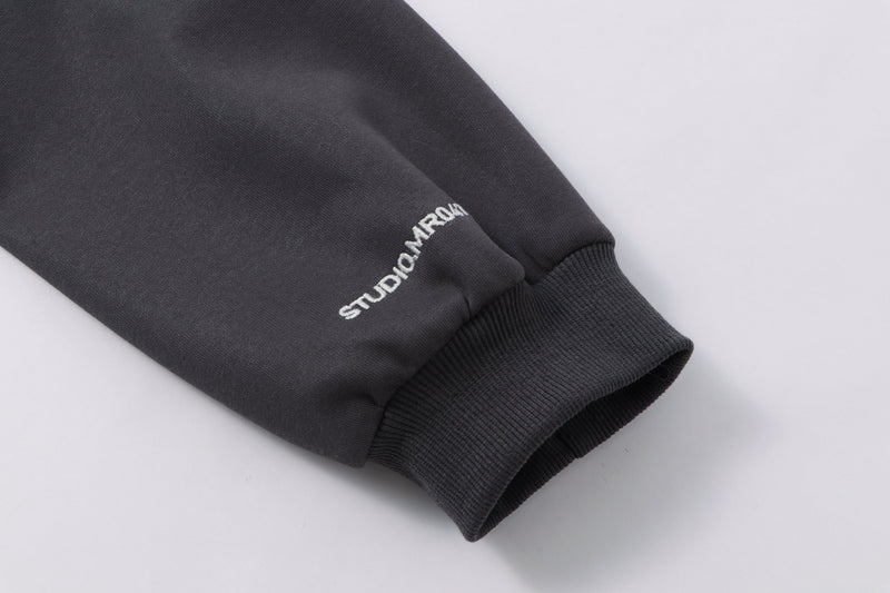 Close-up of black sleeve cuff with white Studio Maram embroidery