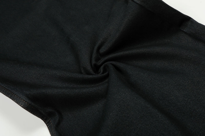 Close-up of black denim fabric with a spiral fold and visible twill texture