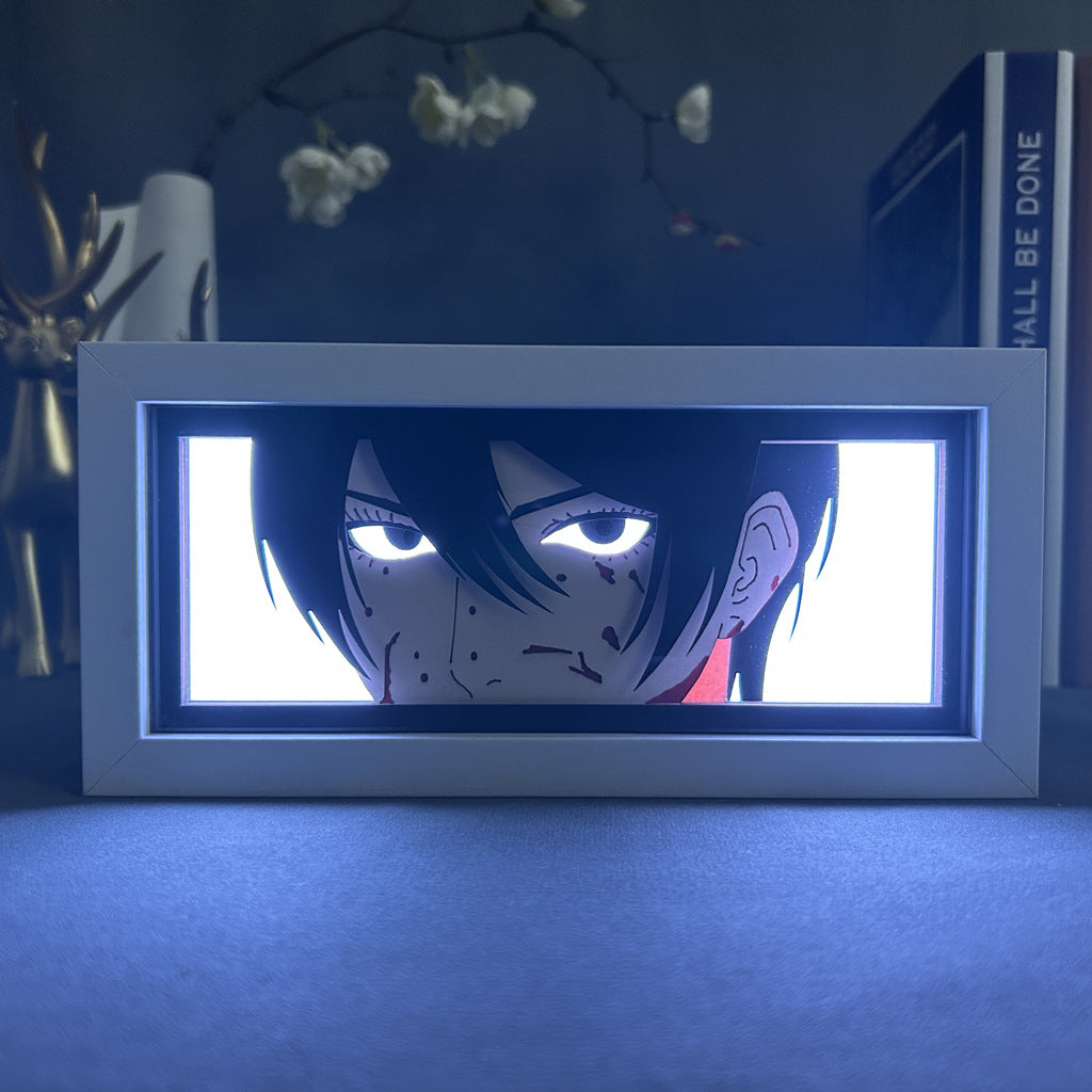 The Attack on Titan Anime Light Box – Mikasa Ackerman 3D LED Lamp features a dynamic color-changing illustration of Mikasa with her serious expression, intense eyes, and dark hair against a softly lit background with decorative items like a book and metallic figure.